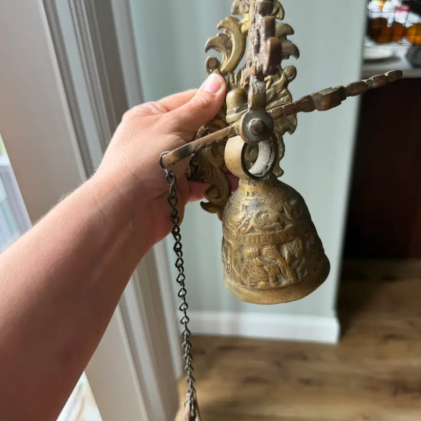 An antique cast brass decorative door bell with a pull chain.
