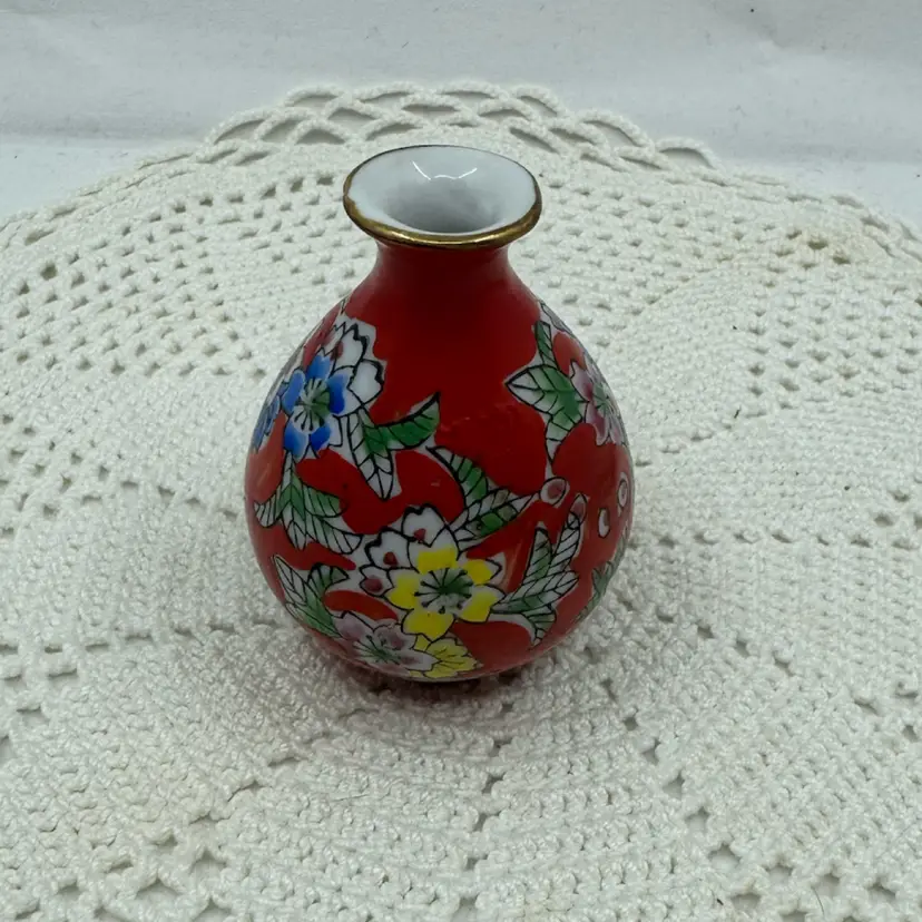 Mini red vase with floral motifs and a gold rim.