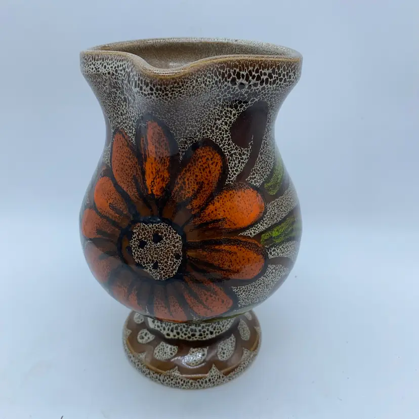 #2228 A handmade Italian ceramic pitcher with speckled glaze and floral motif 7” x 6”
