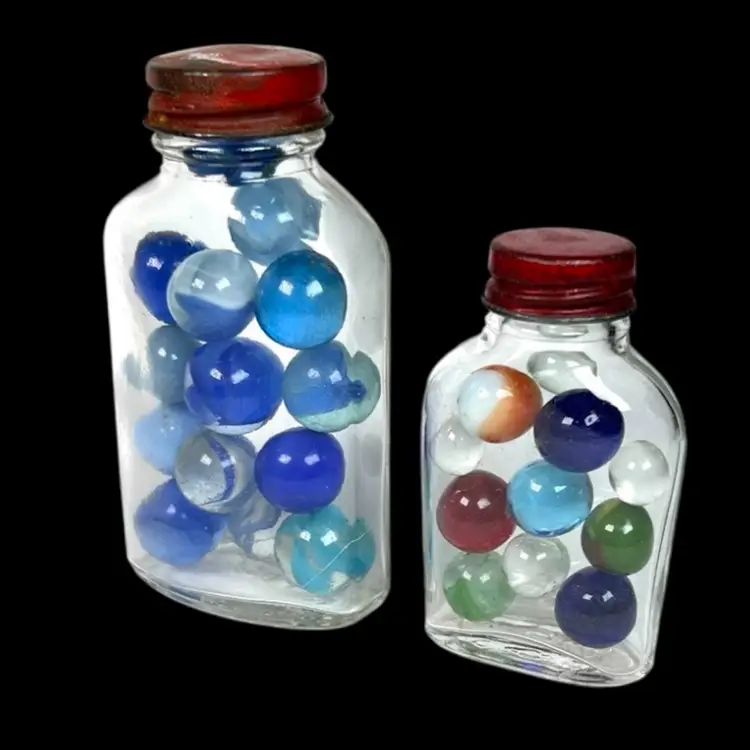 Two Vintage Jars Of Marbles.  Red Metal Lids- One Lid Says “A Genuine Bleecker Product”. Small Jar- 11 Assorted Color Marbles; Big Jar- 14 Blue Marbles.