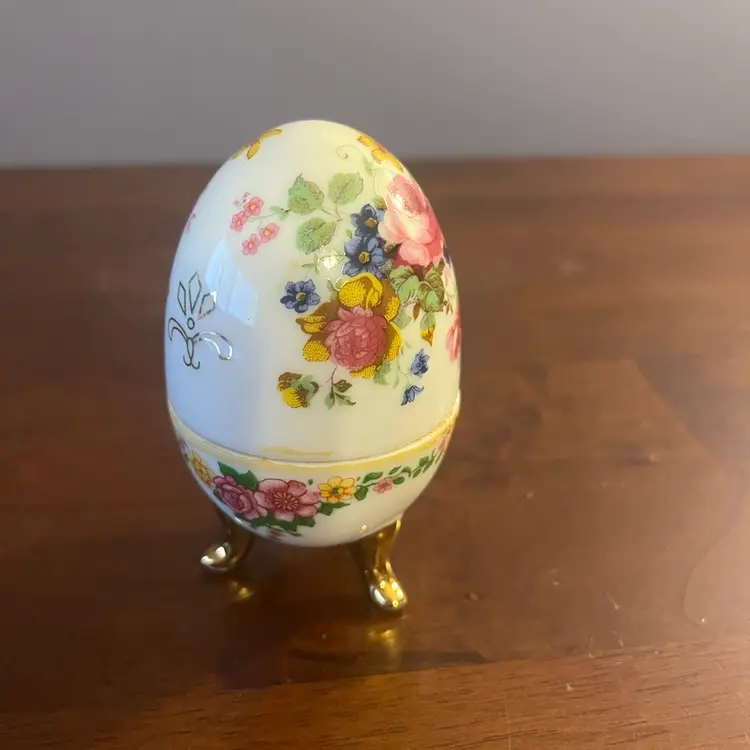 Vintage  floral porcelain egg-shaped trinket box with gold feet. 4” Tall
Missing Hinges And Brass Trim At Middle.