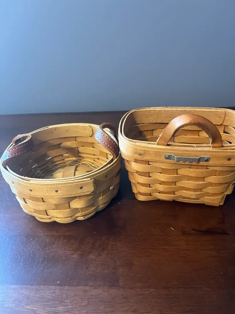 Two woven Longaberger baskets with leather handles.  
Round is 6” x 3” other is 6” x 4” x 3”