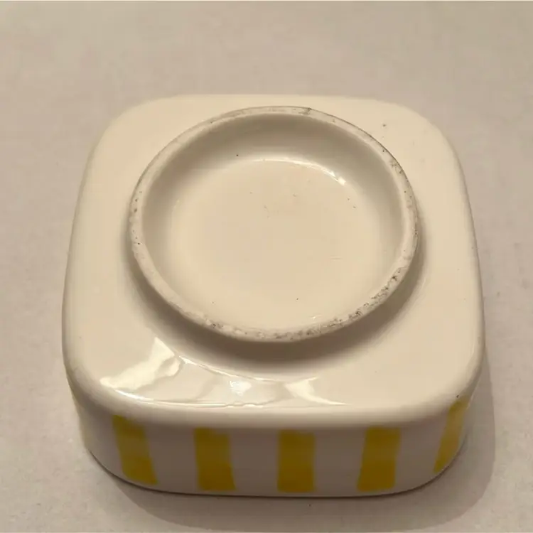 Yellow striped small trinket dish with small flower.  It is in excellent condition.