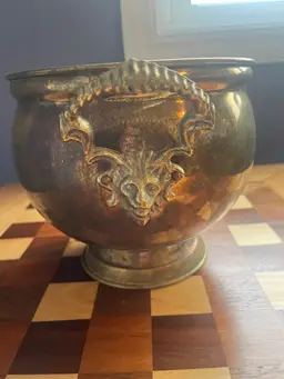 Vintage brass planter with lion head handles and decorative masque.