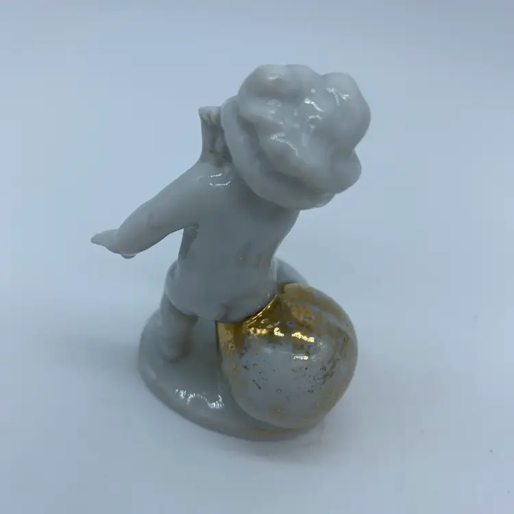 #1409 Royal Copenhagen porcelain cherub figurine with a gold ball, bearing a blue crown and N mark
