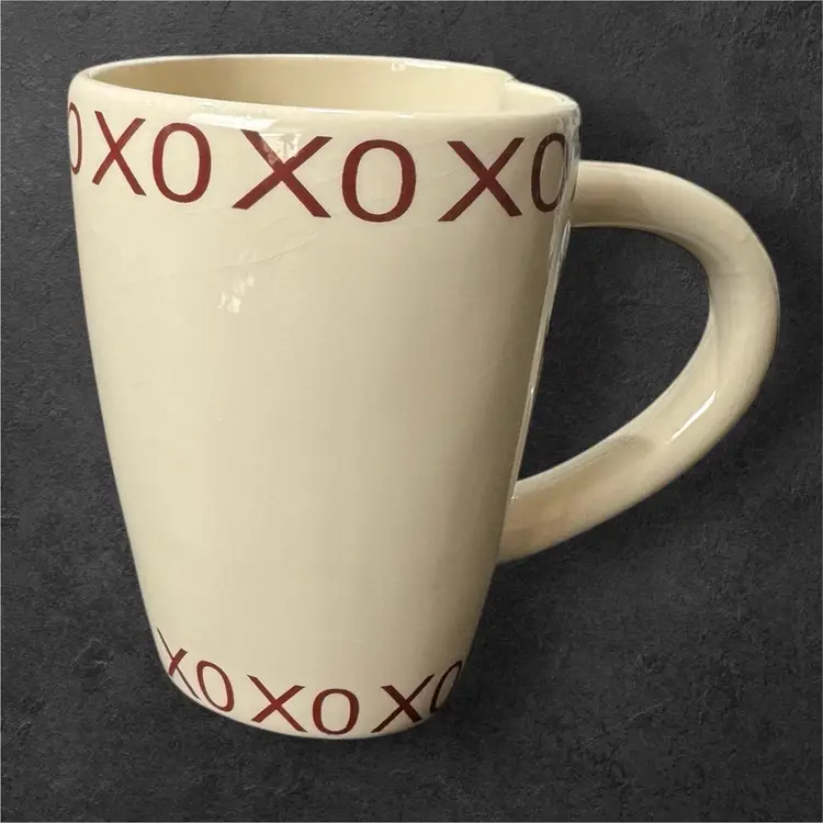 Cream Colored Ceramic Heart Shaped Coffee Mug With Red X’s and O’s Trim on the Top And Bottom