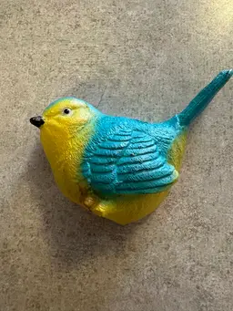 Resin bird figurine in blue and yellow.