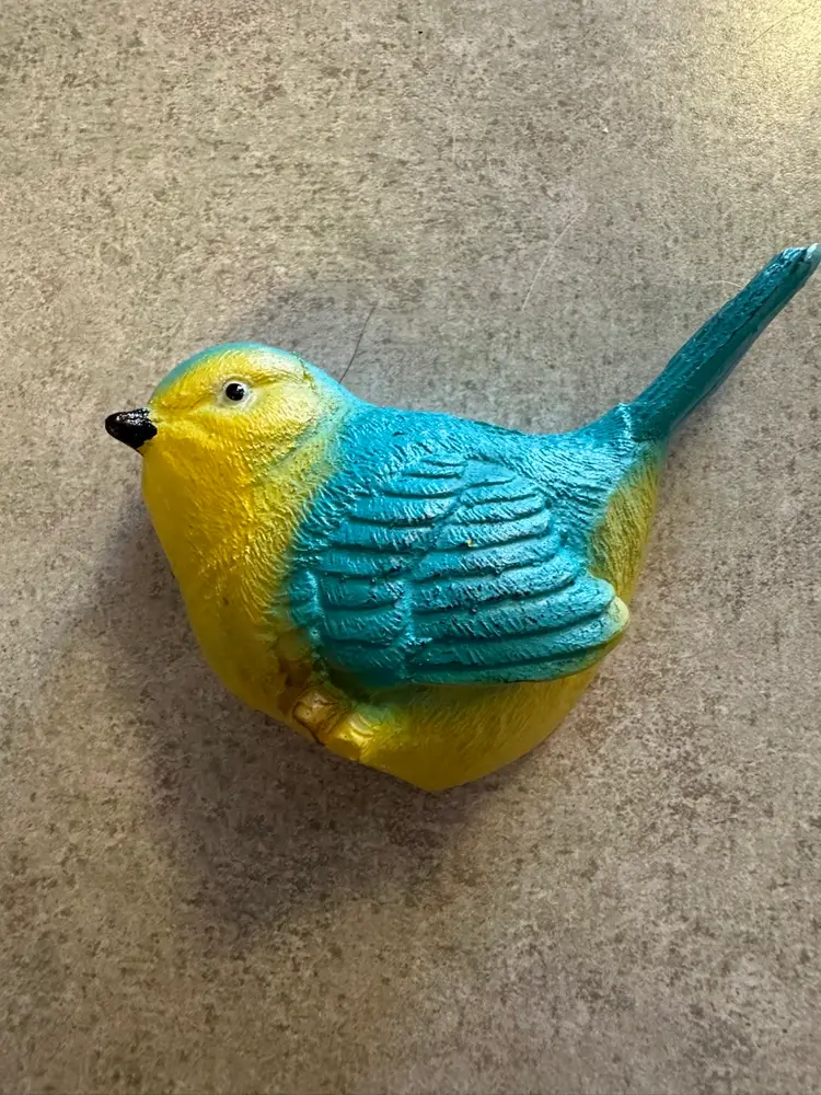 Resin bird figurine in blue and yellow.