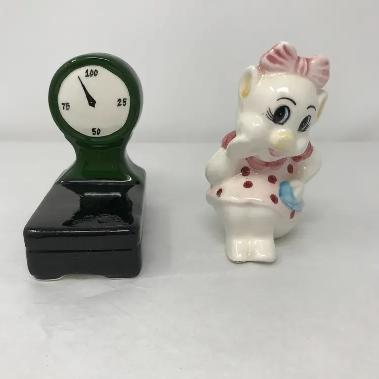 Anthropomorphic cute pig girl with scale salt and pepper shakers. Unmarked - Clay Art or Vandor, 1980s or 1990s.  No chips or cracks, original stoppers. Girl 3.75 H x 2.75 L x 2.5 W; Scale 3.5 H x 1.75 L x 3 W.