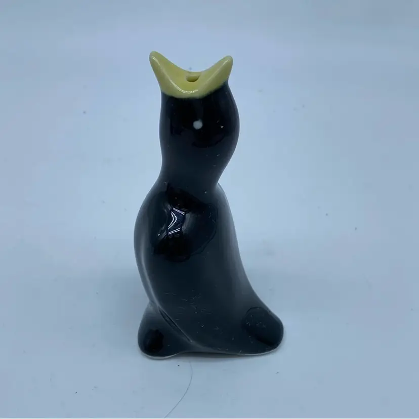 #1440 black ceramic pie bird with a yellow beak and white eyes.