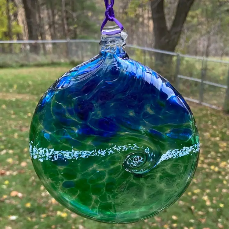 Blue, Green And White, Flat Hand-Blown Glass Ornament With Hanger & Purple Ribbon. 5.25”w x 6.25”h (including hanger) x .75”d. Not Signed.