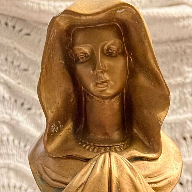 A bust of the Virgin Mary. This statue, often referred to as a Madonna bust, Is Gold In Color.