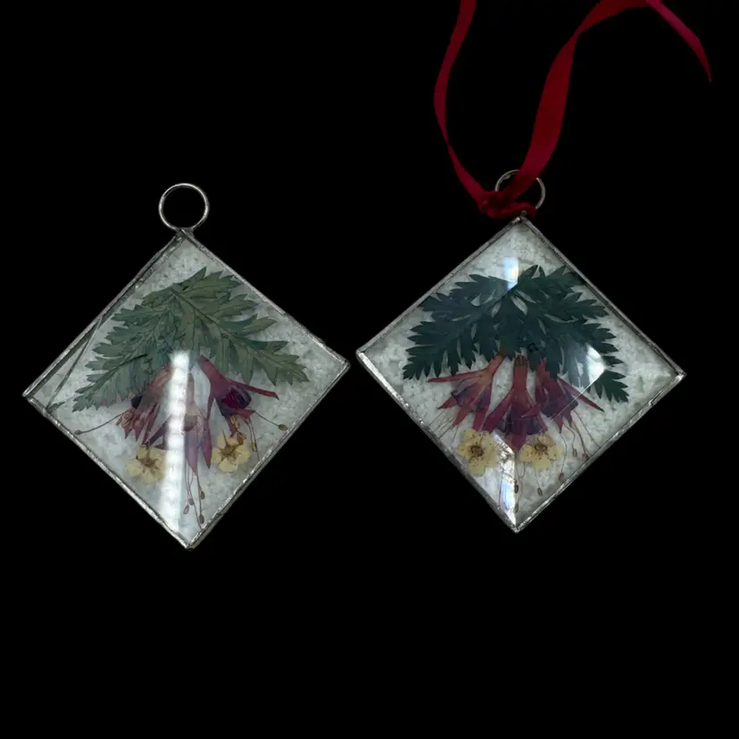 A pair of diamond-shaped glass ornaments with pressed flowers. Crack In One As Shown