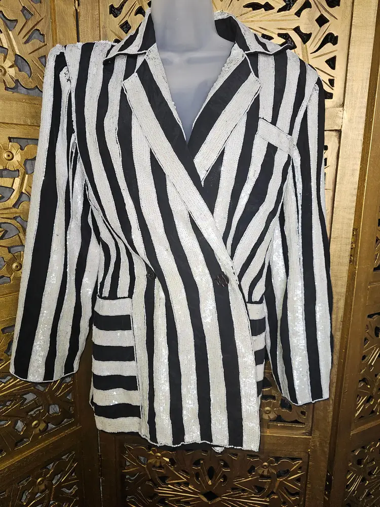 🧟‍♂️👻it's SHOWTIME!!👻🧟‍♀️

1970s/80s Black and White Silk & Sequin blazer by Ecstasy 

Looking for the perfect outfit to see the new Beetlejuice movie? Look no further!
🎵Jump in the line🎵 with this spooktacular black and white beaded blazer that gives off total Beetlejuice Vibes!🪲🍂 made of mulberry silk, this gorgeous blazer has thick bands of white sequins and beads all over it. It's in great condition, and has a double button closure as well as a dagger collar.

🧟‍♀️Approximate measurements 🧟‍♂️
Chest-42"
Waist-36"
Length-26"
Sleeve length-21"
Sleeve width-18"