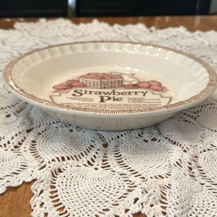 This vintage pie plate dish by Jeanette Royal China features a ruffled-edge design and includes a strawberry pie recipe. Made of ceramic in the United States during the 1980s, this 11" dish is a collectible item for kitchen and home decor enthusiasts. Excellent condition