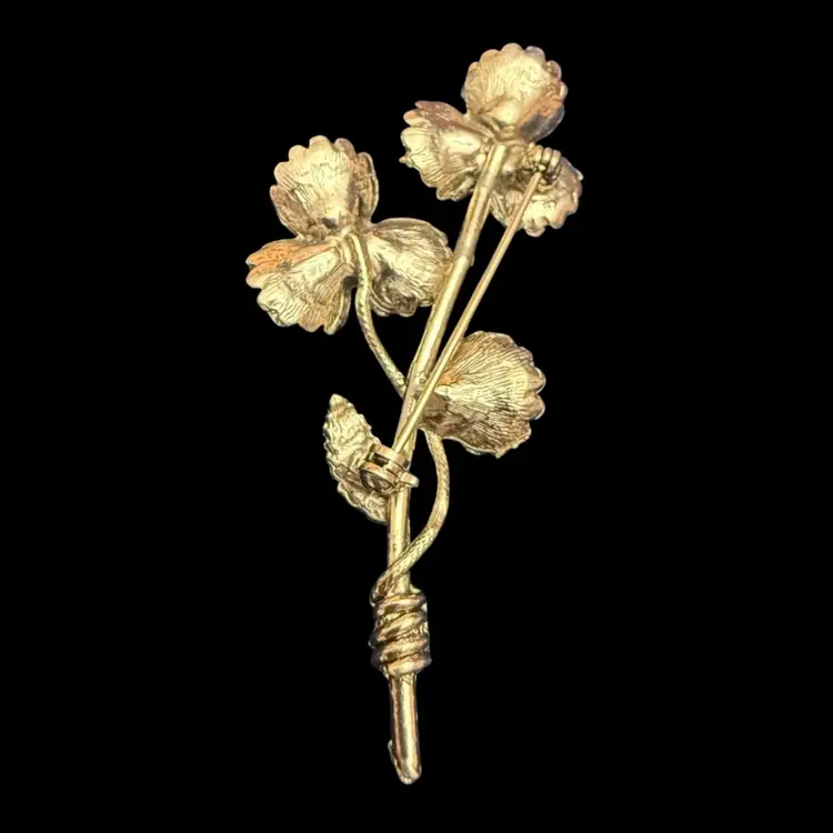 vintage gold-tone floral brooch featuring blue prong-set rhinestones and an Aurora Borealis rhinestone