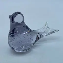 A stylized glass bird figurine with internal controlled bubbles Clear With A Lilac Hue.