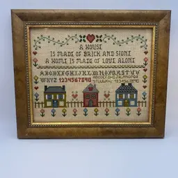 framed, vintage cross-stitch sampler featuring the quote: "A House is made of Brick and Stone, a Home is made of Love Alone"