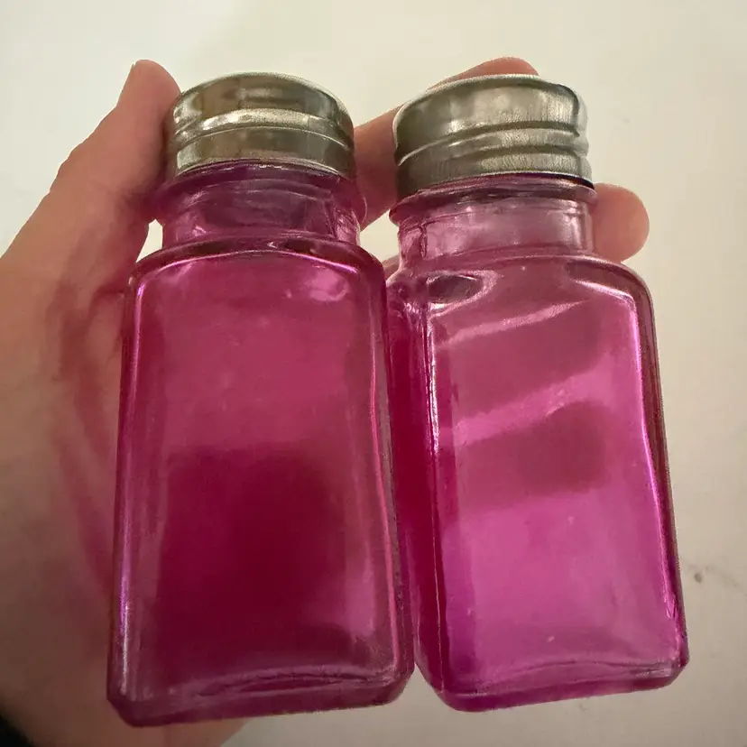 A pair of pink glass salt and pepper shakers with metal tops. 3.75”