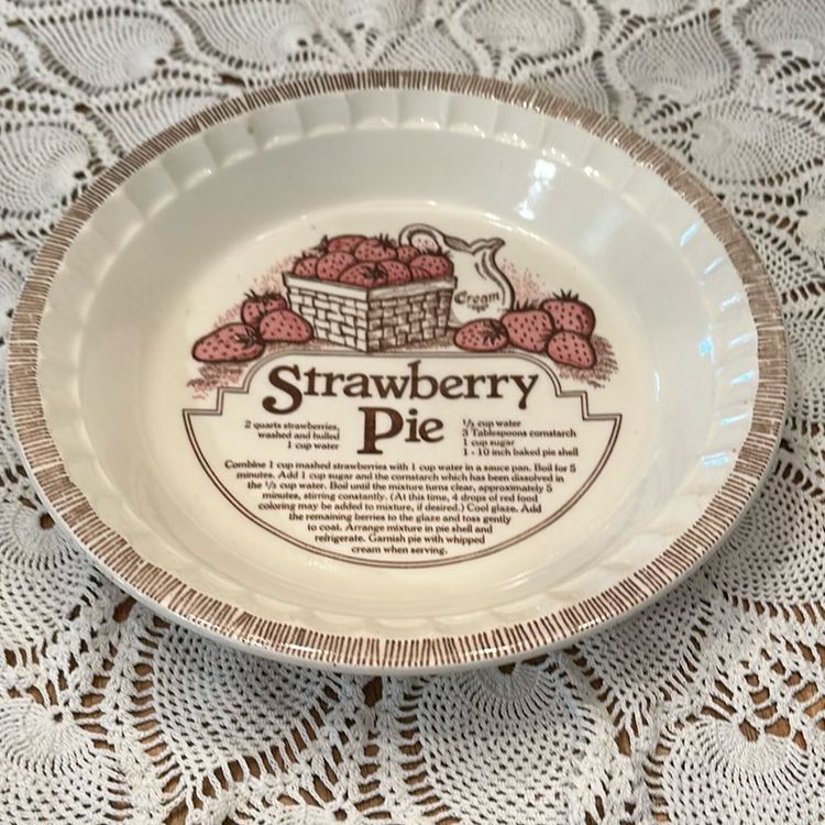 This vintage pie plate dish by Jeanette Royal China features a ruffled-edge design and includes a strawberry pie recipe. Made of ceramic in the United States during the 1980s, this 11" dish is a collectible item for kitchen and home decor enthusiasts. Excellent condition