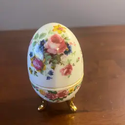 Vintage  floral porcelain egg-shaped trinket box with gold feet. 4” Tall
Missing Hinges And Brass Trim At Middle.