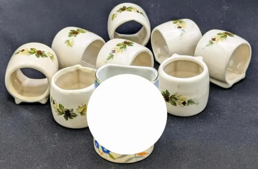 8 Signed Footed Napkin Rings With Holly.   Up to 2 Inches Tall.  Some Rough Spots Can Be Felt Along Rim of Holly Holders