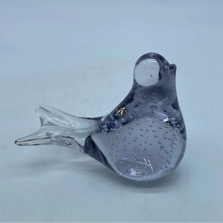 A stylized glass bird figurine with internal controlled bubbles Clear With A Lilac Hue.
