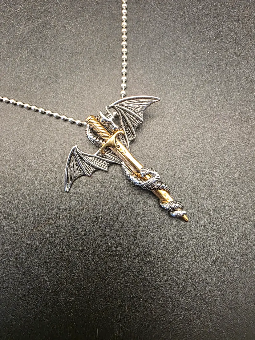 Silver tone dragon holding gold tone sword