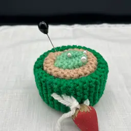 Hand knit Green Pin Cushion with Strawberry. Includes 3 Faux Pearl Pins And 1 Black Faux Pearl Hat Pin.
3.5” X 2.5”