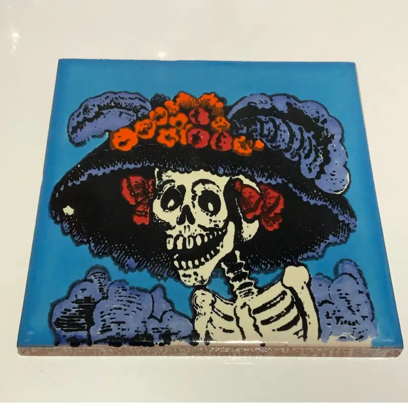 Hand Crafted Talavera Mexican Tile Mosaic Day of the Dead Blue Background Catrina Featuring Thee Catrina In Purple And Black Feathery Hat With Plumes And Orange And Red Satin Lace Roses In A Purple Dress 4.5” By 4.5” Red Clay