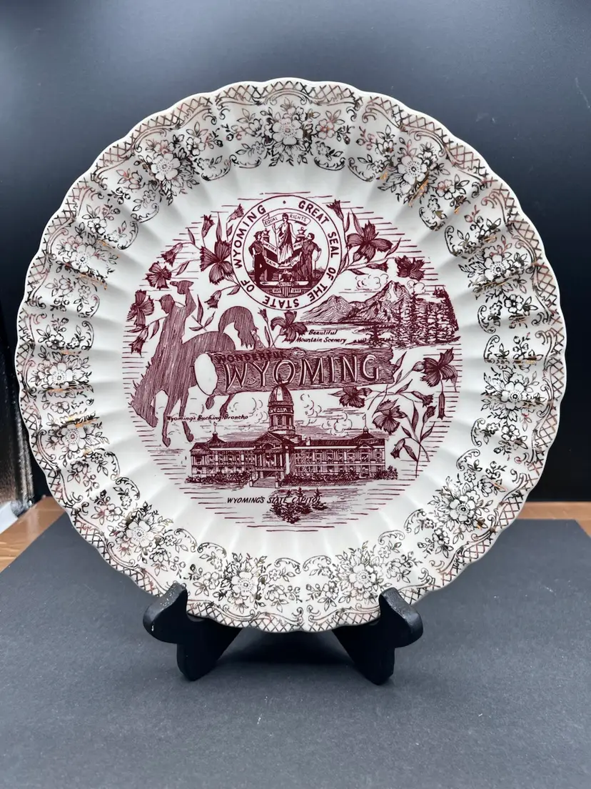 Vintage Collector Plate For Wyoming With Depictions Of The State Seal, The State Capitol Building, A Bucking Bronco And Mountains 
Beautiful Cream Color With Gold Leaf Lace Design Around The Rim