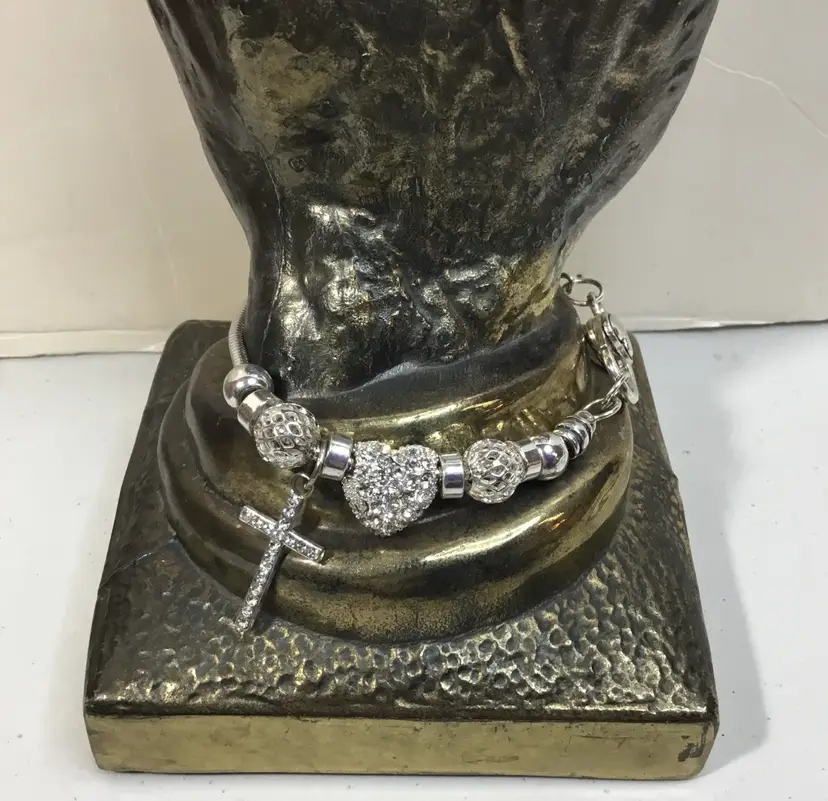 Sparkly, silver tone charm bracelet. Clear rhinestones on cross and heart. 8"