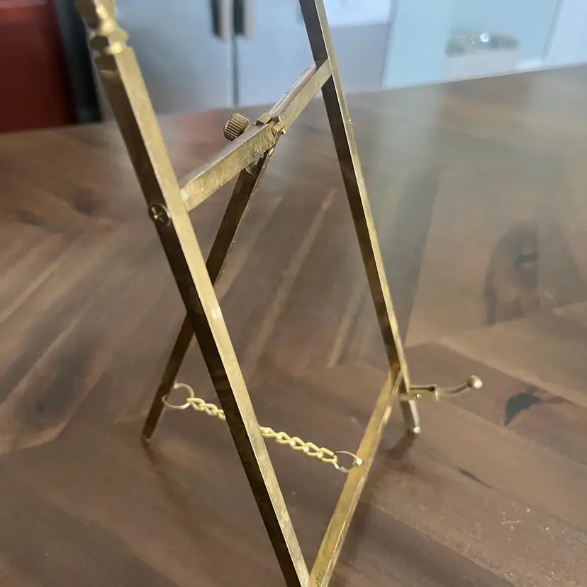 A vintage foldable brass decorative display easel with a chain.