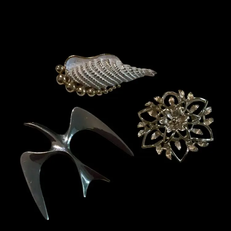Lot Of Three Sarah Coventry Brooches. Silvertone Dove Brooch, Goldtone White Enamel She’ll Brooch, Goldtone Textured Flower Brooch.