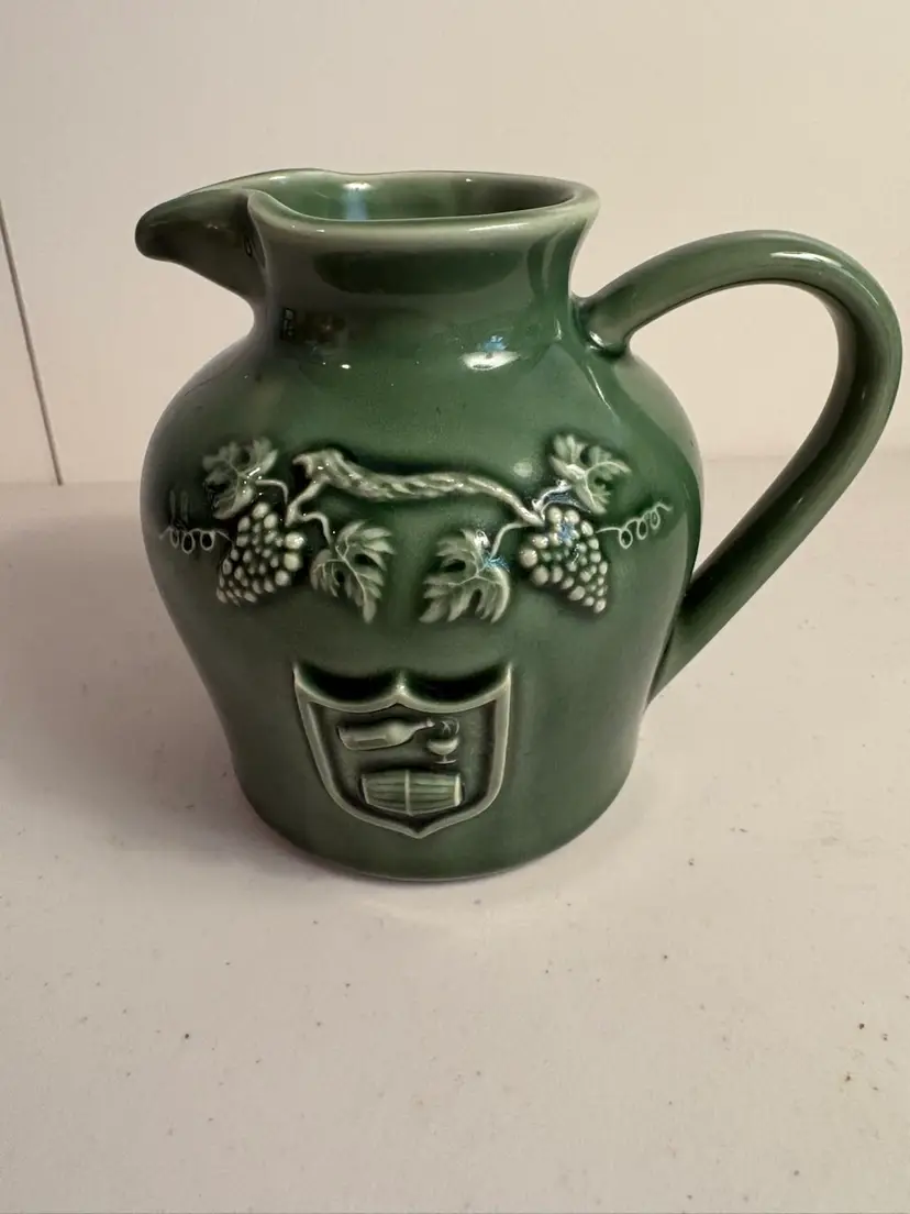 Green wine pitcher in ceramic, with embossed grape motifs.