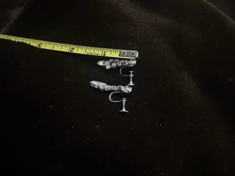 Vintage Continental silver-tone dangle clip-on earrings feature prong-set baguette and round clear rhinestones