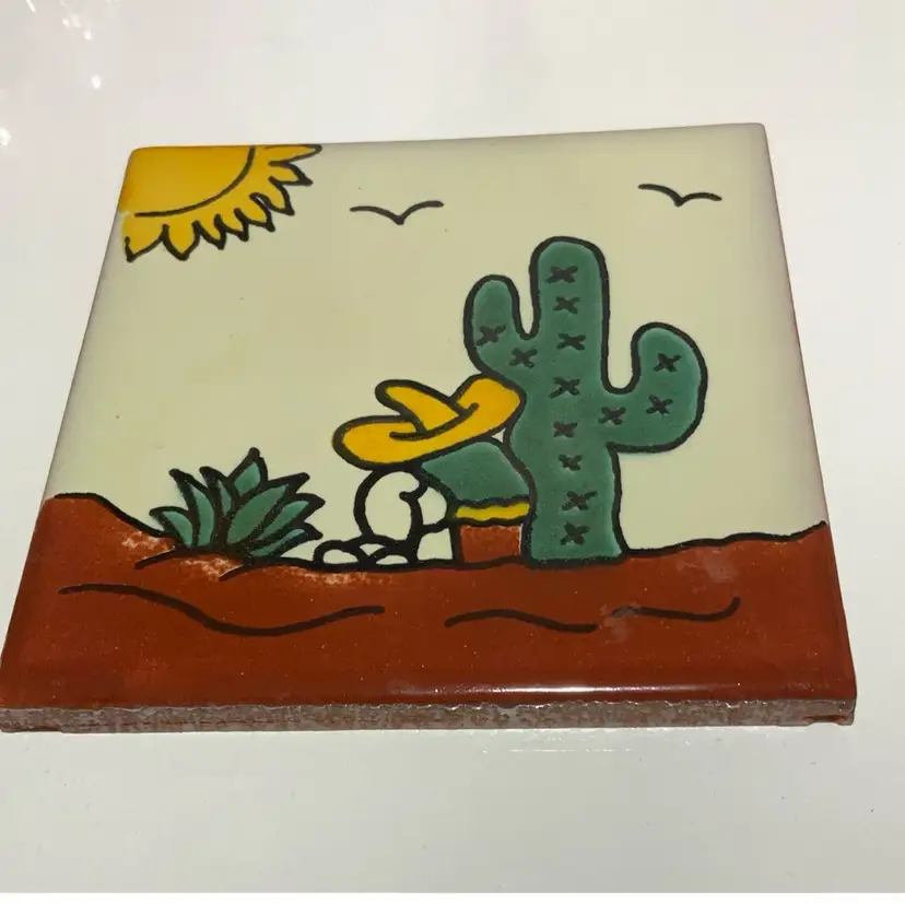Hand Crafted Talavera Mexican Tile Cream Color Background Featuring A Destilador Sitting By An Ancient Saguaro 🌵 Cactus And A Tequila Agave Plant Nearby He Is Is Wearing A Yellow Sombreros Green Shirt And Tan White Pants Resting 4.5” By 4.5” Red Clay