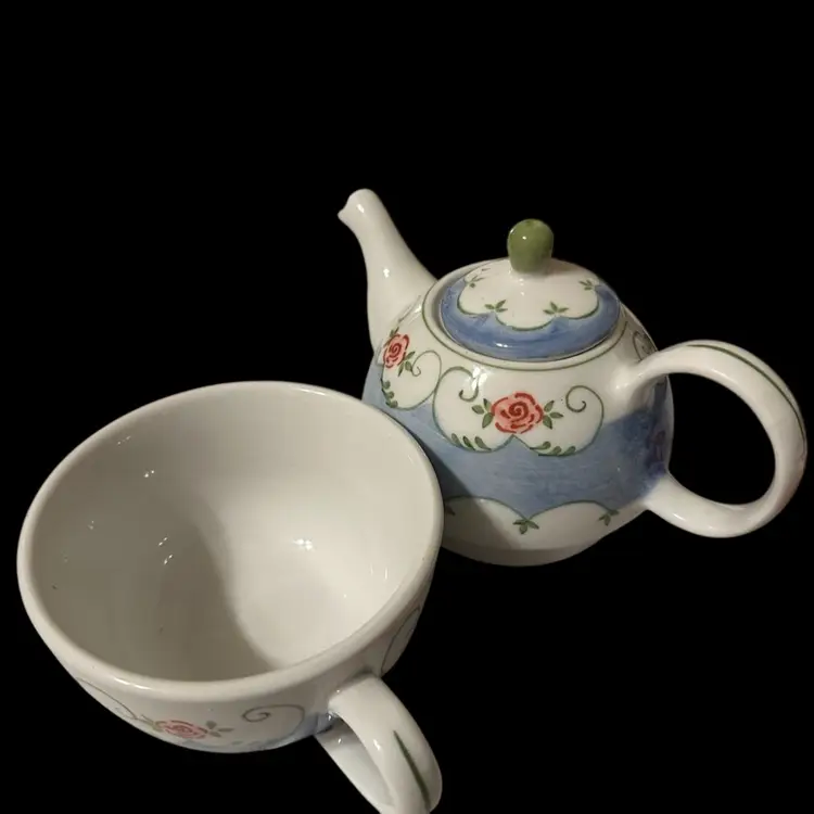 A modern ceramic teapot and cup set with hand-painted roses.