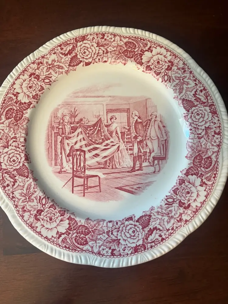 Homer Laughlin red transferware plate depicting Betsy Ross and the American flag. 9”