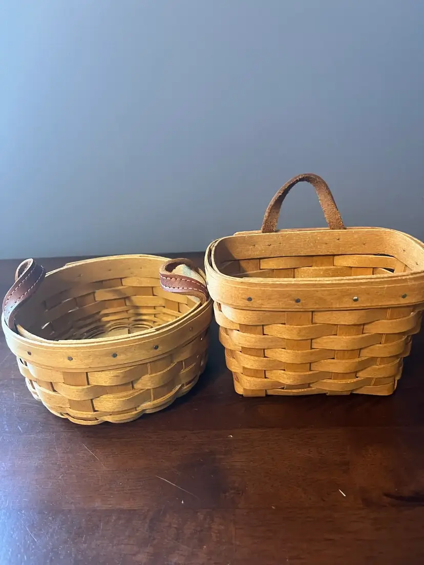 Two woven Longaberger baskets with leather handles.  
Round is 6” x 3” other is 6” x 4” x 3”