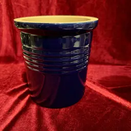 Vintage Pampered Chef Family Heritage Collection cobalt blue stoneware crock.
It can be used as a utensil holder, bread baking crock, or wine chiller. 
It features a glazed cobalt blue exterior with concentric horizontal ribs and a neutral interior. 
The stoneware is known for its durability and even heating properties.