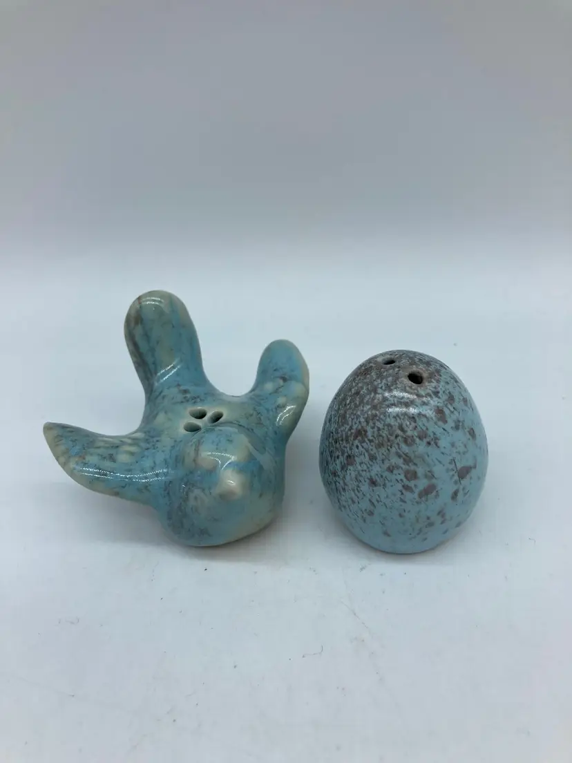 Small ceramic salt and pepper shakers features a blue-speckled flying bird, matching speckled egg-shaped companion.