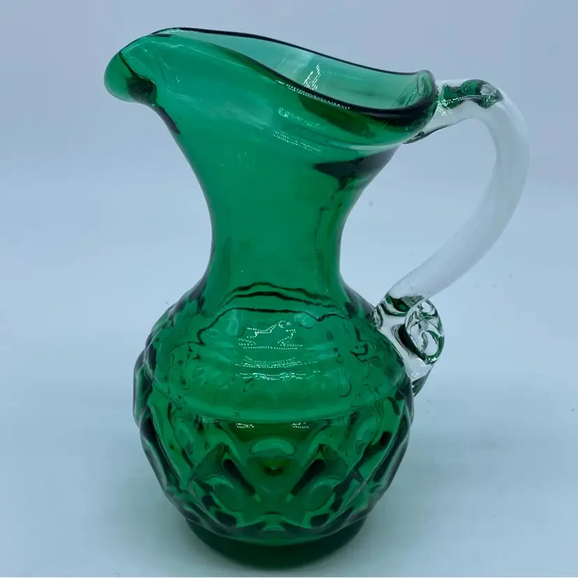 #0302 Emerald green miniature glass pitcher with a clear handle and textured body.