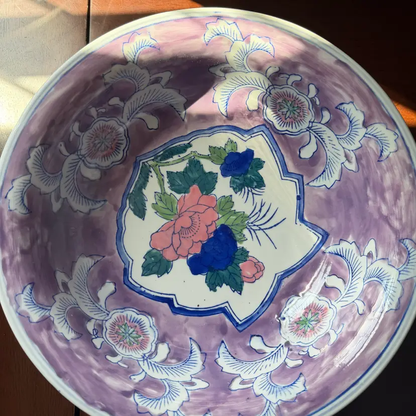 A vintage hand-painted ceramic bowl with floral motifs. 13.” X 4”