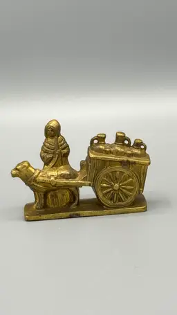 A brass figurine of a Flemish milkmaid with a dog-drawn milk cart.