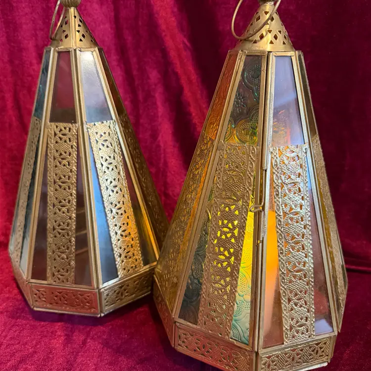 Vintage Moroccan-style Metal and colored glass candle lantern. Price is for 1- Will sell both at discounted price. Note- Candle not included.
This Stunning Candle holder has pierced metal with yellow, pink, and blue glass panels. Some of the panels are solid glass and some have a Moroccan type design. The lantern has a metal loop for hanging at the top but also has feet and can sit on a table. One panel is hinged and opens to place a Real candle or battery candle inside. It is a truly beautiful piece!
