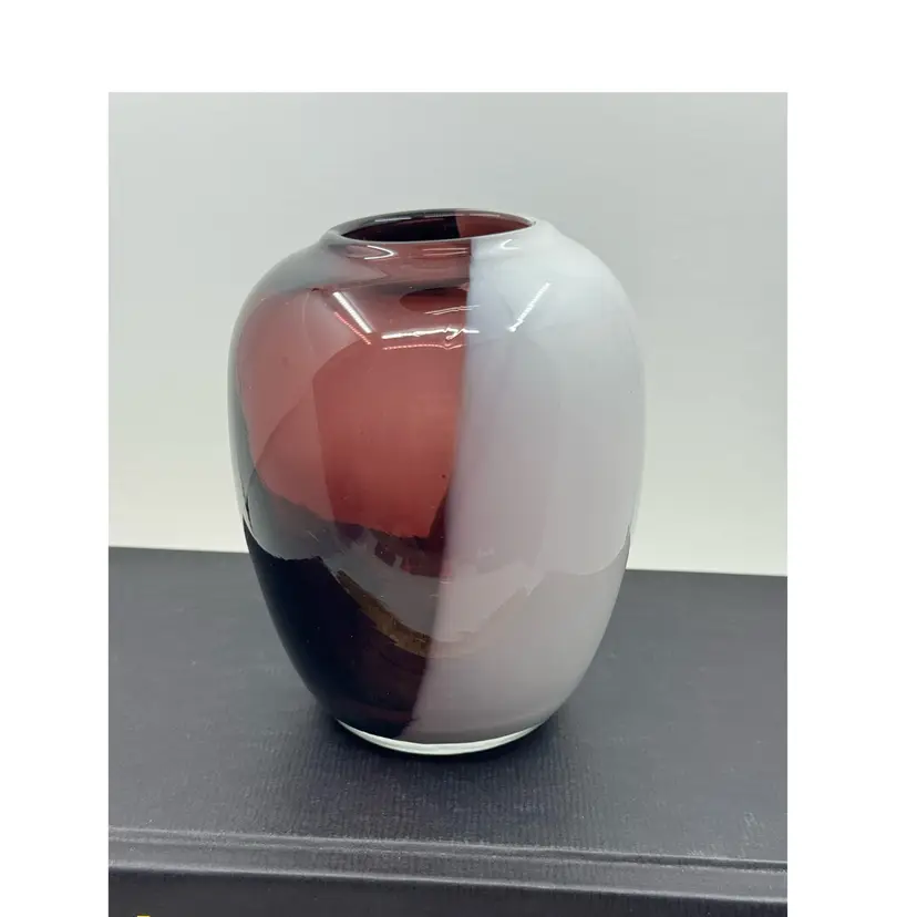 A hand-blown art glass vase with white, plum, and black color transitions.