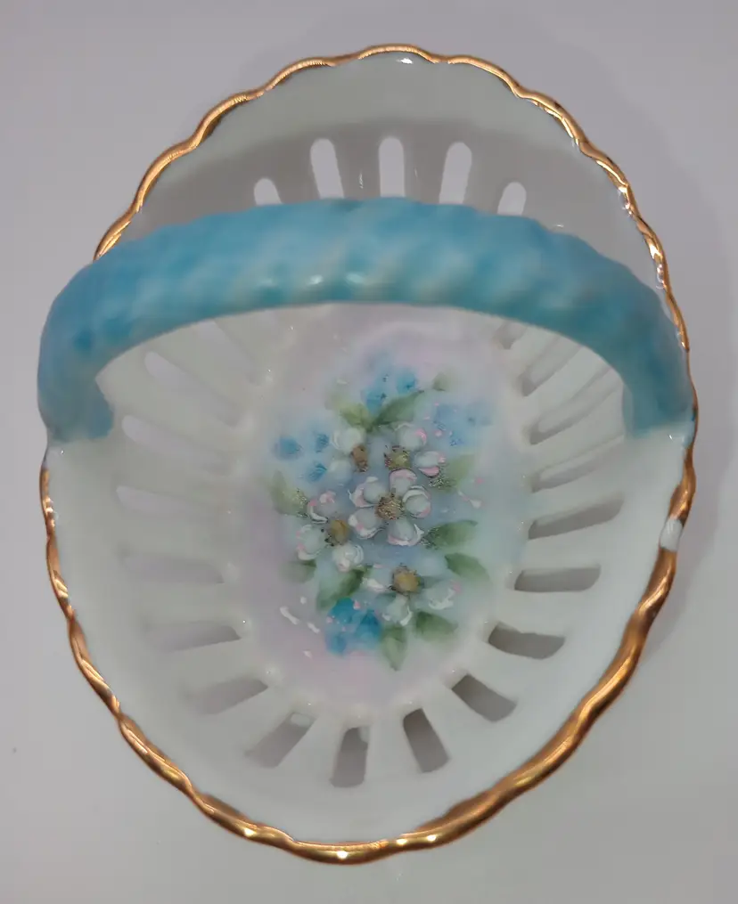 Vintage, Small ,Hand Painted, Artist Signed, Basket .
This Small Basket Would Make An Incredible Addition To A Miniature Collection Or A Trinket Dish.
It Is A White Porcelain Basket With Blue Handles Hand painted Floral Design And Guilding Around The Edge Of The Dish. It Measures 2.5 Inches Tall By 3.5 Inches Wide.