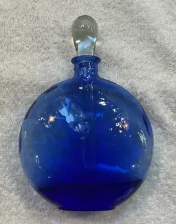 #01 Blue perfume bottle 6.5” tall with stopper and 4.5” wide and 1.5” deep. No chips or cracks on stopper or rim. Glass has a slight texture to it which adds sparkle