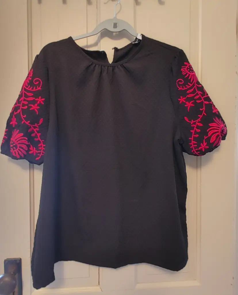 Top- Brand: Charming Charlie. Black top with pink embroidered sleeves. Size 2X. Material- 100% polyester. No callouts.